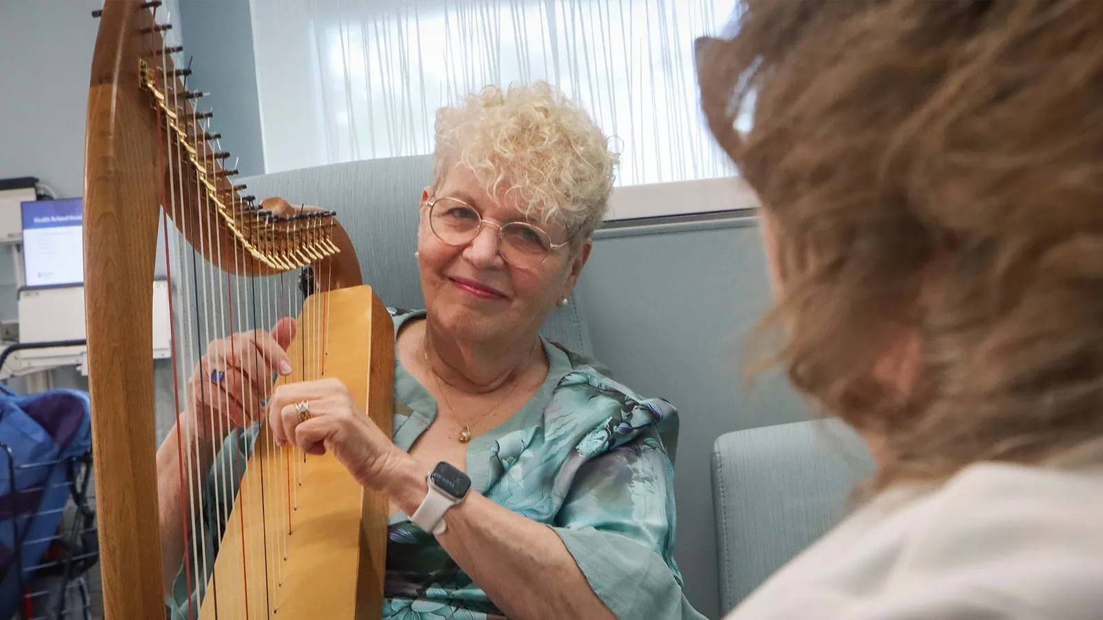 A harpist playing soothing music for a hospital patient at the bedside