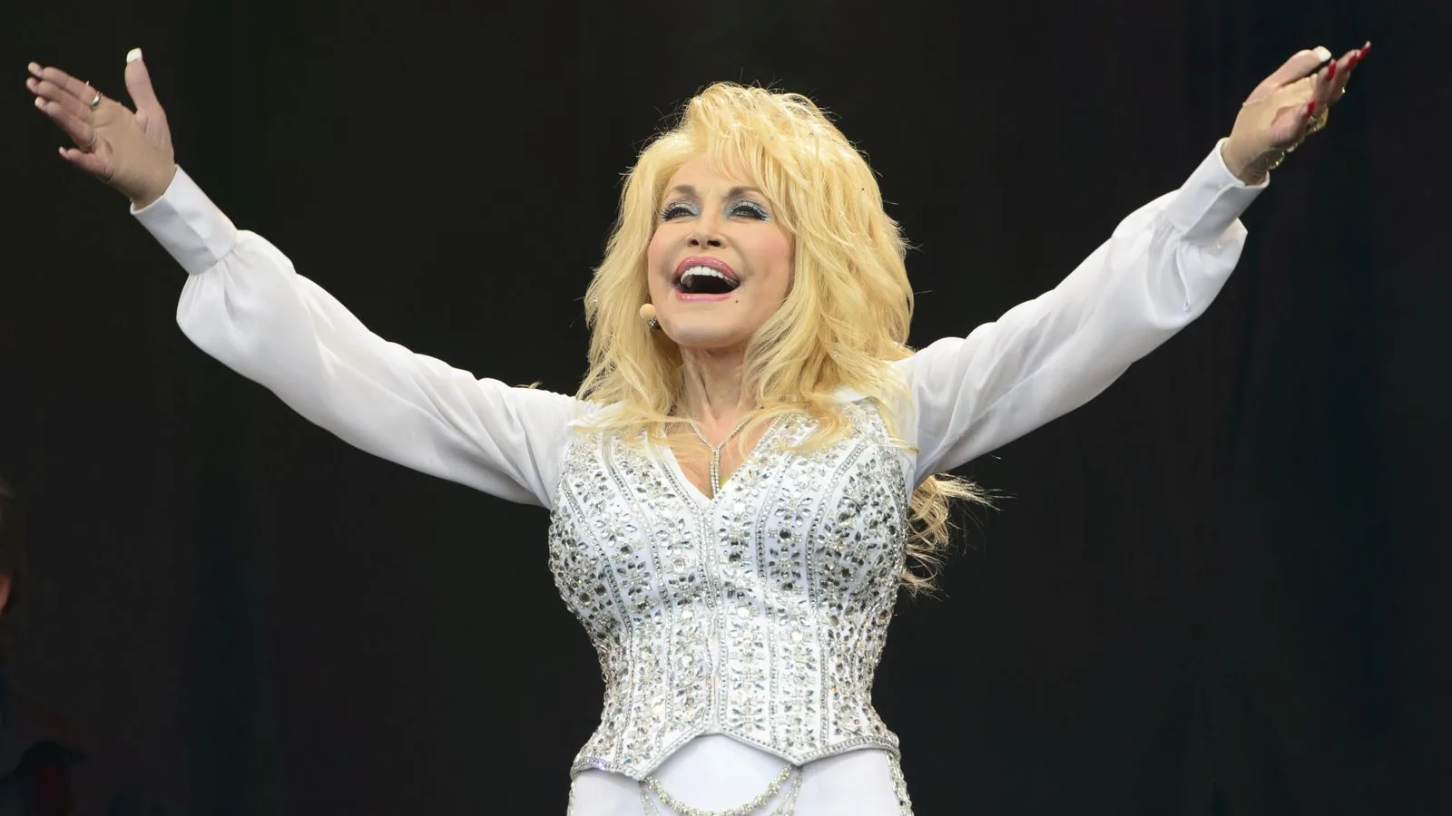 Dolly Parton smiling in a performance image, reflecting her country music career and charity work