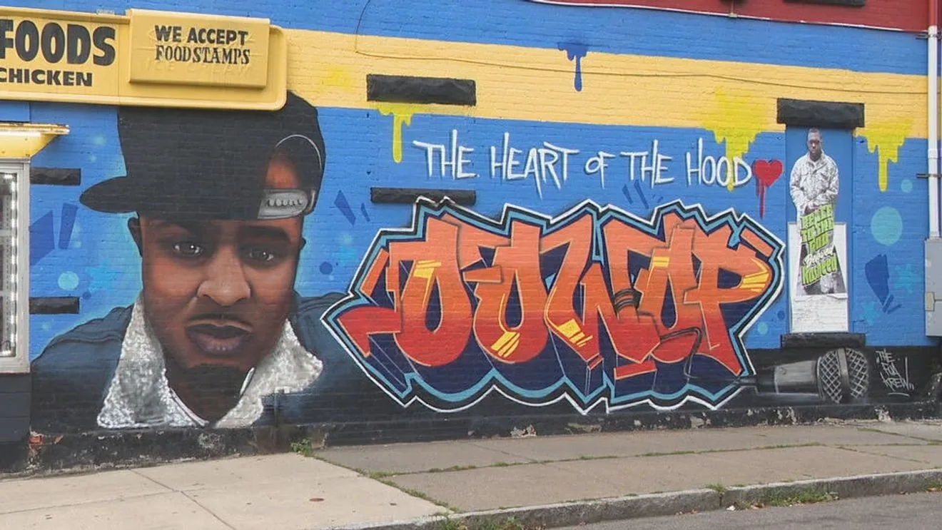 People gather near a Rochester mural honoring musician Richard Oowop Diggs during a birthday tribute