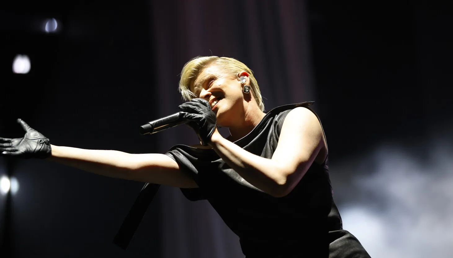 Robyn performs on a thrust stage at the United Center with white curtains and glitter falling around her